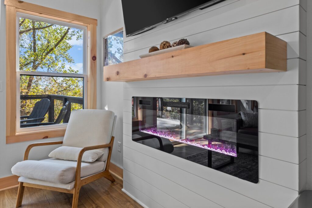 Electric fireplace and reading chair inside the Cabin Treehouse